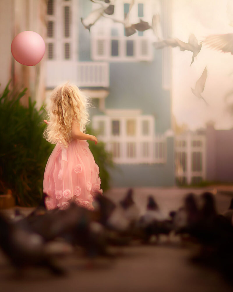 Canon-Fine-art-portrait-of-a-little-girl-in-a-pink-dress-holding-a-pink-balloon-and-standing-between-doves-at-pietermaai-in-Curacao-by-Dutch-photographer-Willie-Kers-e1603808480238